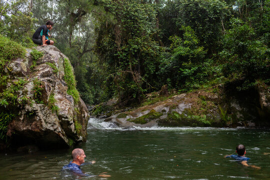 Dad with son swimming in forest river on overcast day