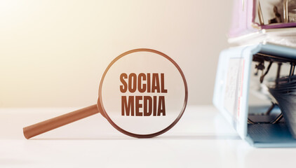 A magnifying glass focusing on the words social media underneath it, emphasizing the importance of online networking and communication.