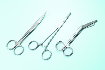 Three pairs of surgical scissors are shown on a green background. The scissors are all silver and appear to be of the same size