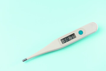 A digital thermometer with the temperature of 38.2 degrees on the screen. The thermometer is white...