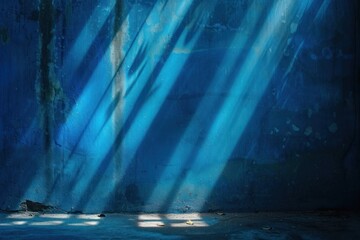 Fototapeta premium Light in the dark. Rays light on blue wall with smoke and shadow
