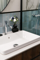 Ceramic washbasin and chrome water tap in bathroom with modern interior