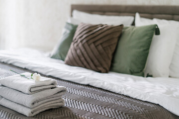 White guest towels on neat and comfort bed with decorative cushions