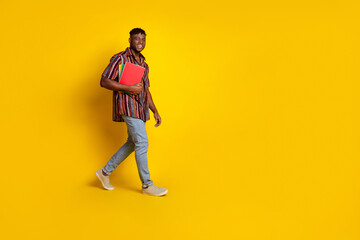 Fototapeta premium Full body profile portrait of nice young man walk empty space wear shirt isolated on yellow color background