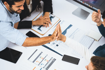Diverse group of office employee worker high five after making agreement on strategic business marketing planning. Teamwork and positive attitude create productive and supportive workplace. Prudent