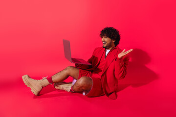 A man sitting on the floor, focused on using a laptop computer.