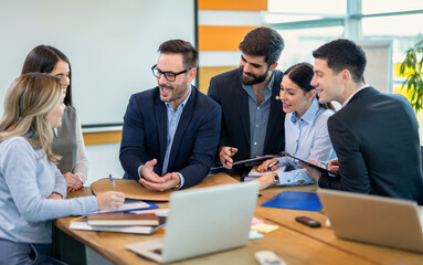 Cheerful businessman attending a meeting with his colleagues in an office. Creative businesspeople working together