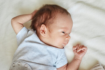 Newborn baby falling asleep infant boy lying on white sheet on bed copy space for advertisement empty area for commercial content