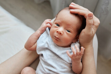 Unknown woman sitting and holding her infant son or daughter petting tiny head of her newborn child...