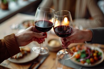 Obraz premium Elegant Couple Toasting with Red Wine at Candlelit Dinner Table
