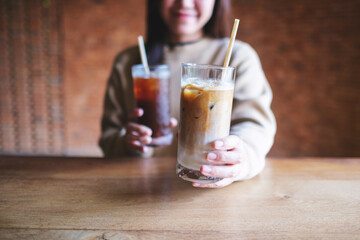 Closeup image of a young woman holding andserving two glasses of iced coffee