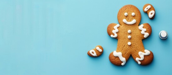 Fototapeta premium A gingerbread man with white icing on blue pastel backdrop, perfect for Christmas, with copy space image for a festive touch.