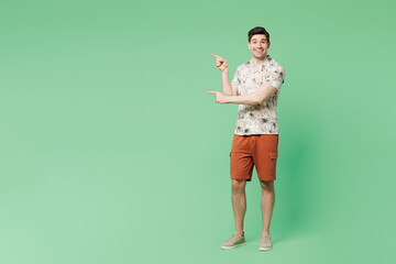 Full body young smiling fun Caucasian man wear white shirt casual clothes point index finger aside on area mock up isolated on plain pastel light green background studio portrait. Lifestyle concept.