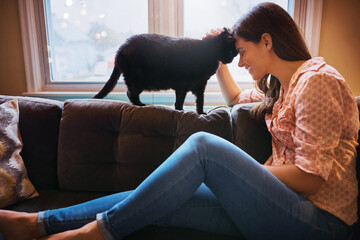 Woman, cat and forehead touch for love in home, scratch and support animal or companion for care on sofa. Female person, relax and calm in living room to stroke pet, trust and connection or loyalty