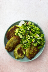 Zucchini and broccoli pancakes served with a mixed salad of cucumbers, young peas, and radishes. This healthy vegetarian dish is both delicious and nutritious