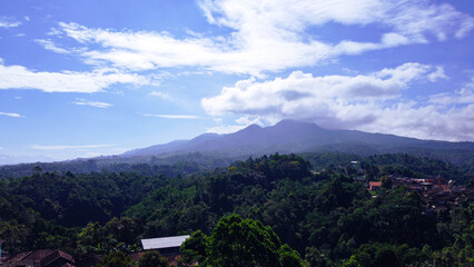 A breathtaking drone shot of Mount Cikuray in Garut Regency, West Java, the fourth highest peak in the region, revealing its majestic slopes and lush greenery from a bird's-eye perspective.