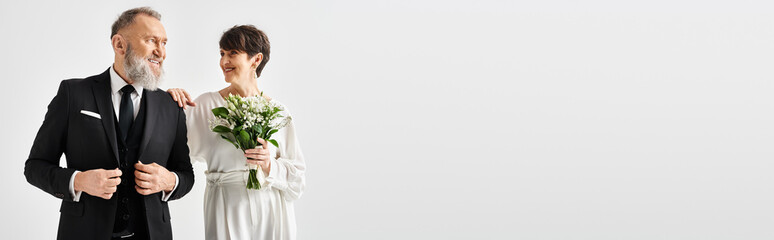 A middle-aged bride and groom in wedding attire, celebrating their special day in a stylish studio setting.