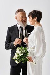 Middle-aged bride and groom in wedding attire standing close, holding champagne glasses in a celebratory gesture.