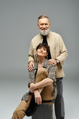 A middle-aged couple in stylish attire striking a pose for a portrait in a studio setting.