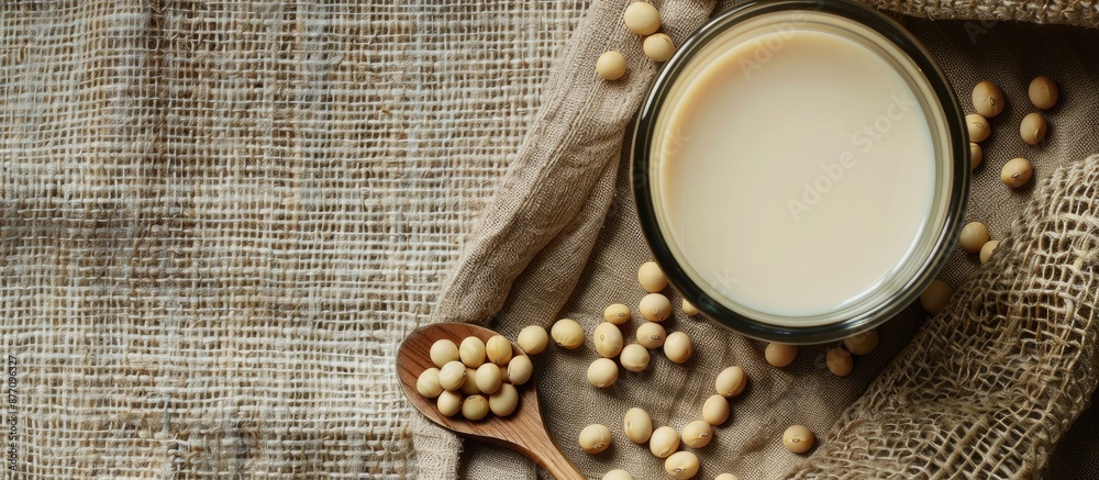 Poster Glass of soy milk with a spoonful of soybeans on a rustic sackcloth background, perfect for adding your text with copy space image.