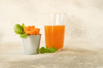 Carrot juice in a glass and fresh carrots with leaves