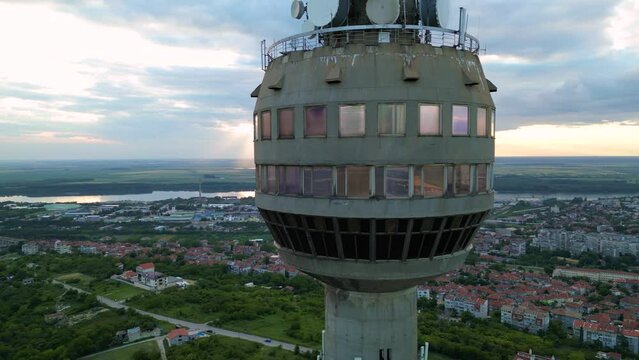Aerial drone footage of a super tall free standing structure for mobile, radio and tv transmittion and broadcast. Concrete tower in Ruse, Bulgaria with sky view restorant. Sunset footage of skyscraper