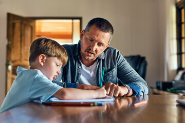 Father, son and helping with homework for education, support and care for preschool, learning and growth. Man, boy and home with writing in book for language, math and skills for child development