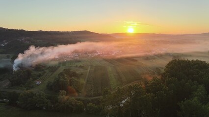 Aerial view rural contryside during misty sunrise with big white smoke came from the factory in the industrial city area