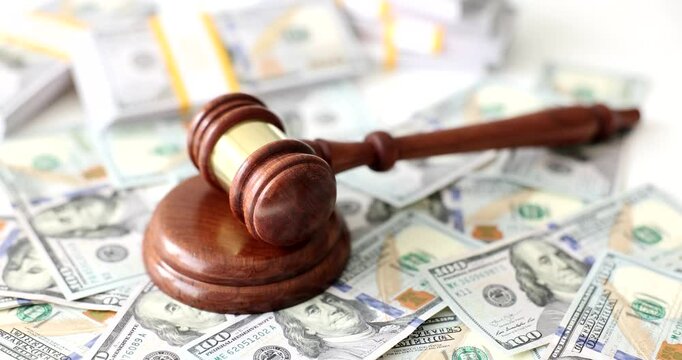 Judge gavel and wooden sound block lie on heap of dollar banknotes. Concept of financial judgment in court. Hammer and scattered money cash
