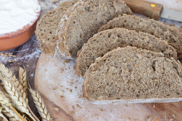 Sliced bread with wheat and flour on rustic wooden table. Close-up. Healthy homemade baked food.