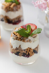 Yogurt with crispy granola, berries and mint leaves for a delicious breakfast. Healthy eating.