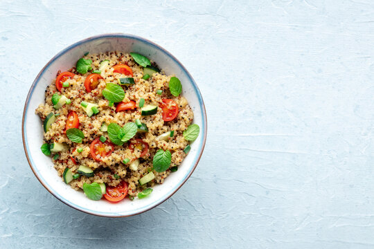 Quinoa tabbouleh salad in a bowl, a healthy dinner with tomatoes and mint, top shot with copy space