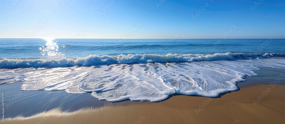 Poster Ocean waves gently lapping the sandy shore create a calming scene with a breathtaking view of the horizon and a clear blue sky in the background with copy space image.
