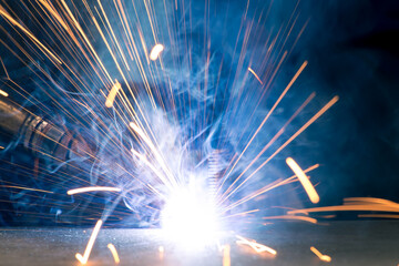 Detail of heavy industry manufacturing, sparks come out of a metal working welder.