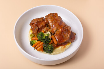 Plate with fried chicken and carrot and potato puree on beige background angle view