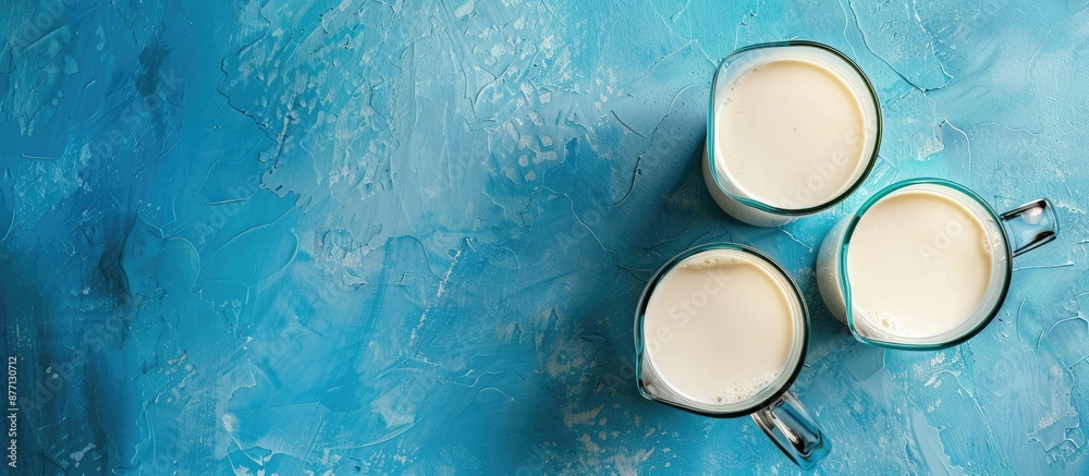 Aufkleber top view of a jug and glass of milk on a blue backdrop with copy space image.