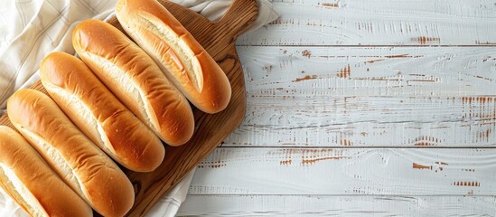 Overhead view of hot dog buns on a rustic wooden board with a white wooden background, depicted in a flat lay style from above, offering ample copy space image.