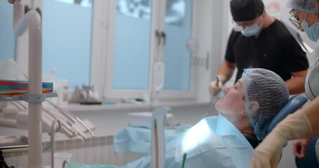 An elderly woman waits in the dentist's chair for her dental surgery to begin