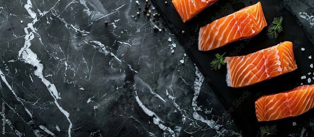 Poster fish delicacy arranged in a flat lay composition with fresh raw salmon on a black marble table, acco