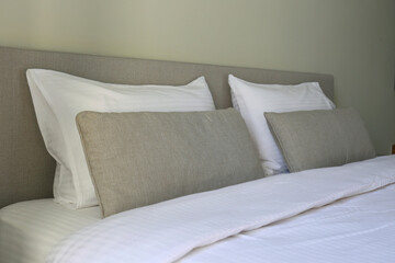 Hotel room with freshly made king sized bed with headboard, perfectly clean and ironed sheets and puffy pillows. Close up, copy space for text.