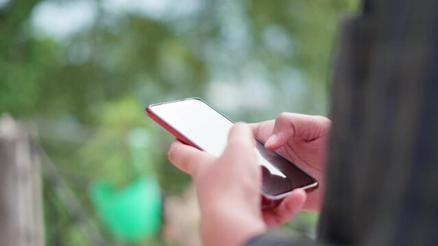 4K closeup shot of hand of an Indian man using mobile phone. Addiction to mobile phone screen background with copy space. Social media addict uses mobile phone while outside. Man using mobile outdoors