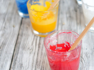 CMYK pigments in glass cups: cyan, magenta, yellow, black and white dyes and wood sticks for mixing DIY.