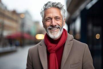 Fototapeta premium Handsome senior man with grey hair wearing a coat and red scarf.