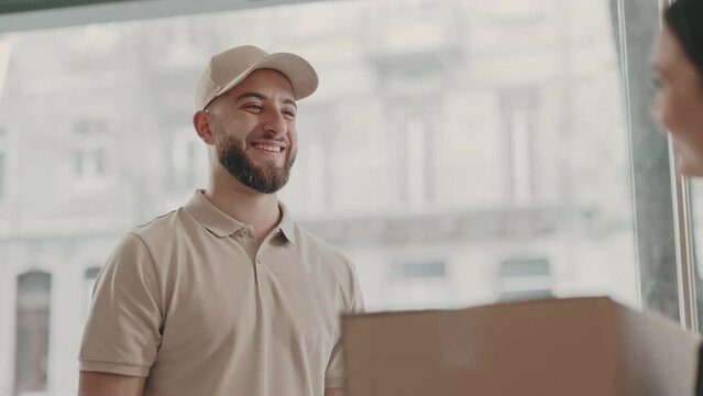 A professional courier hands over a large cardboard box to a client within an indoor setting, capturing the moment of exchange and delivery service.