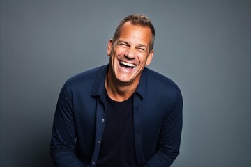 Fototapeta premium Handsome middle age man laughing. Studio shot over grey background.