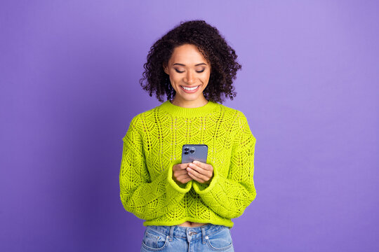 Photo of american young funky girl in green sweater using digital app smartphone working smm manager isolated on purple color background