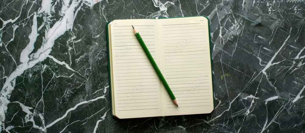 Aufkleber Top view of an open notebook with a green pencil on a marble background dark table with school notepad and office desk in a flat lay copy space image