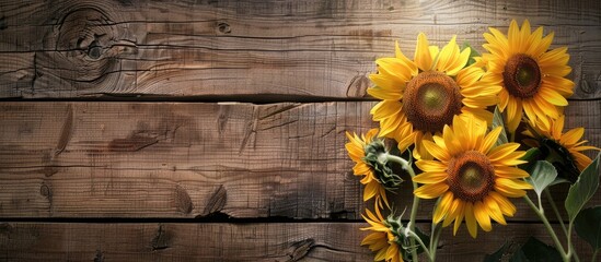 Obraz premium Sunflowers displayed against a rustic wooden backdrop providing a charming copy space image
