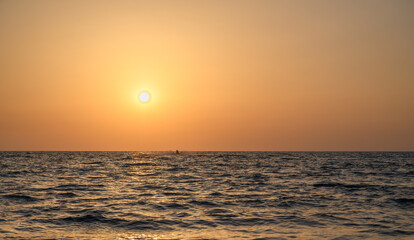 Stunning orange sunset reflecting on the calm waters of a tropical beach