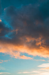 Fototapeta premium Sunset sky background -pink, orange and blue dramatic colorful clouds lit by evening sunshine. Vast sunset sky landscape